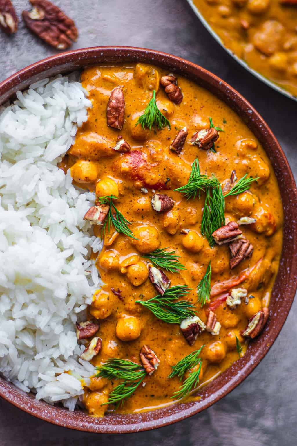 Closeup of vegan butter chicken over rice in a brown bowl