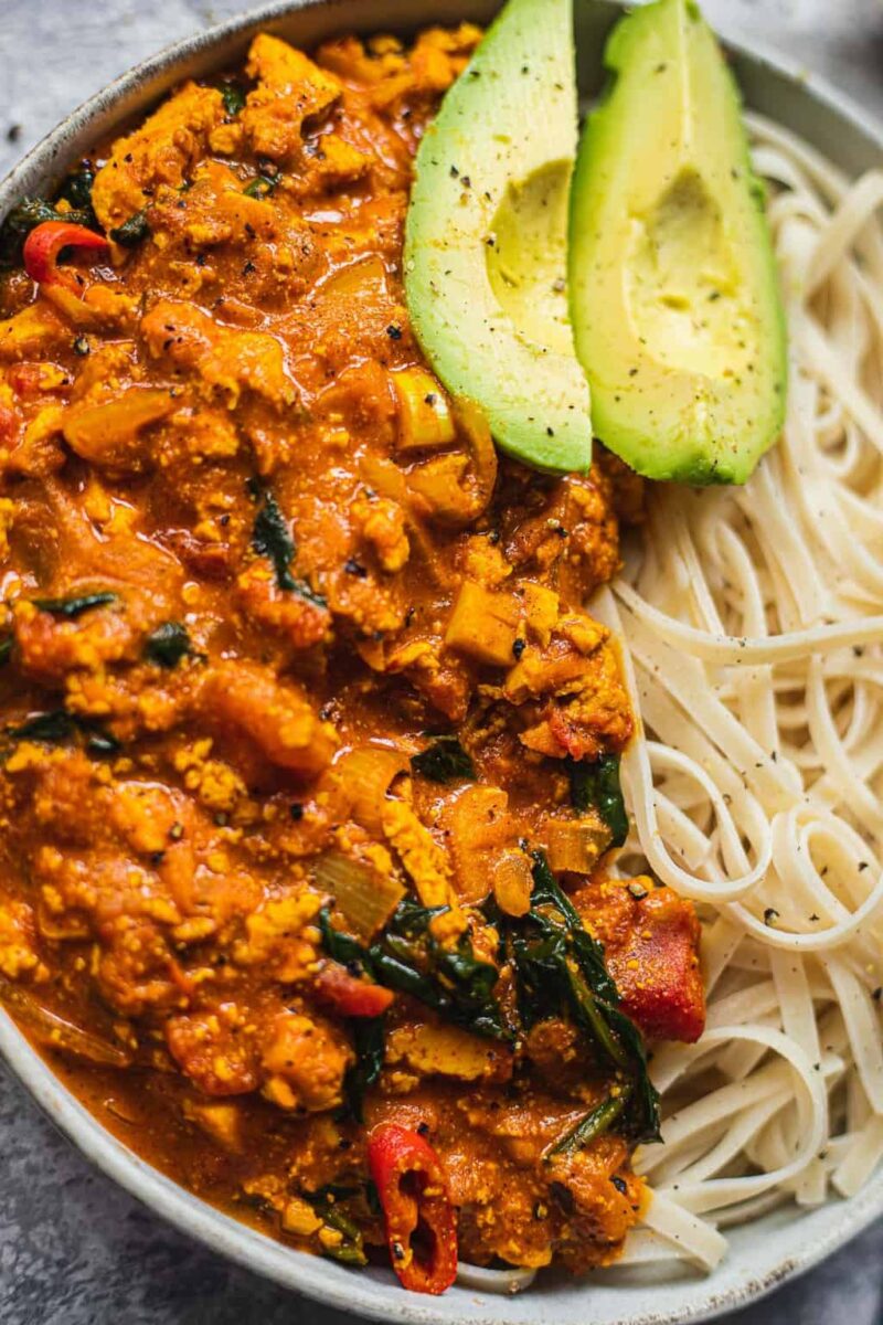 Closeup of vegan curry with noodles and avocado