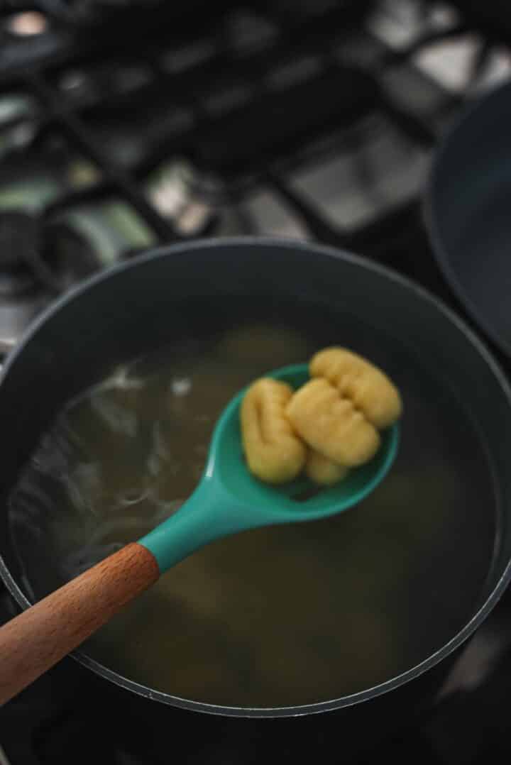 Gnocchi being lifted out of a saucepan