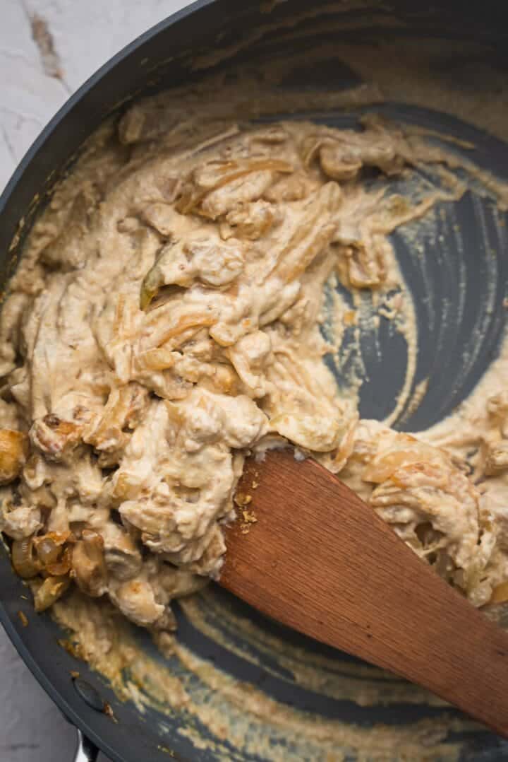 Onions and mushrooms with hummus sauce in a frying pan
