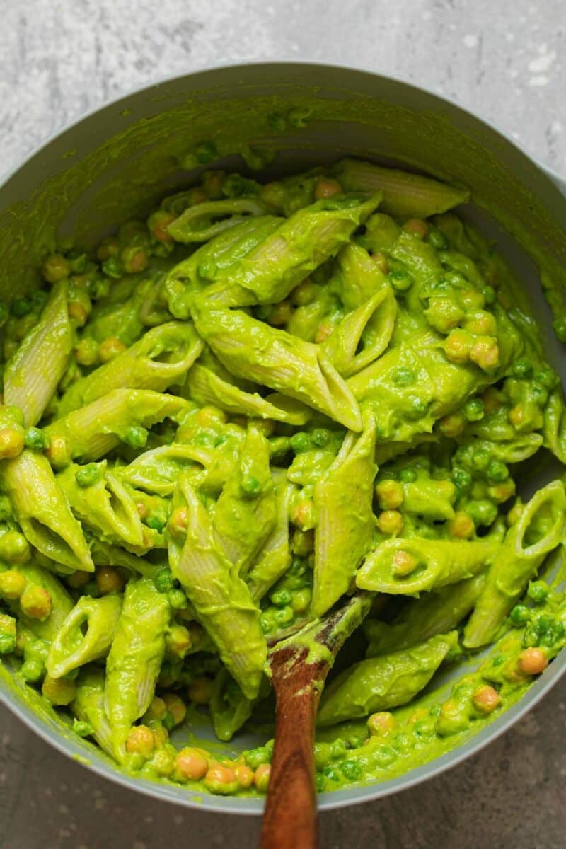 Pesto pasta in a mixing bowl with chickpeas