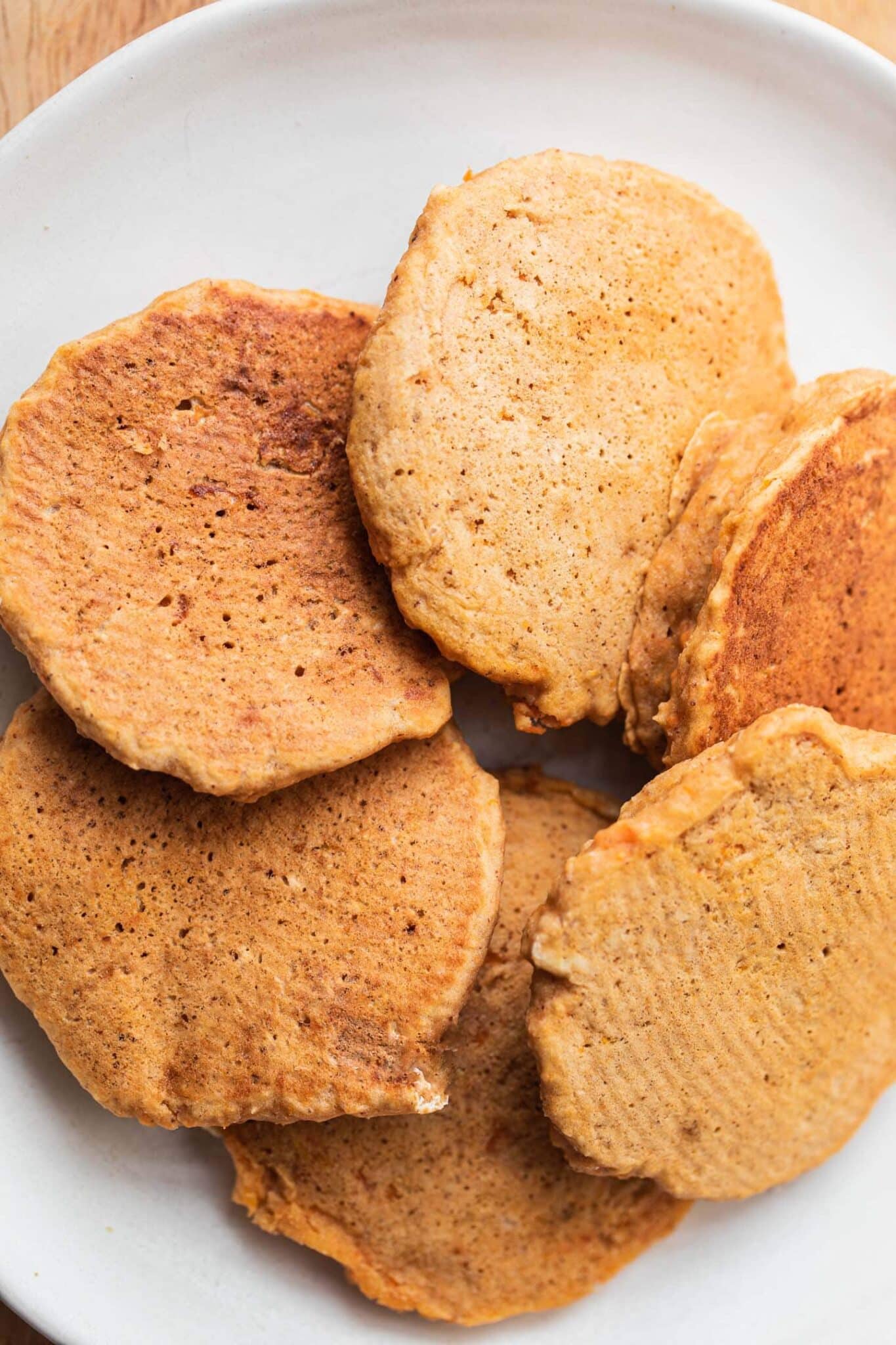 A stack of plain vegan pumpkin pancakes on a white plate