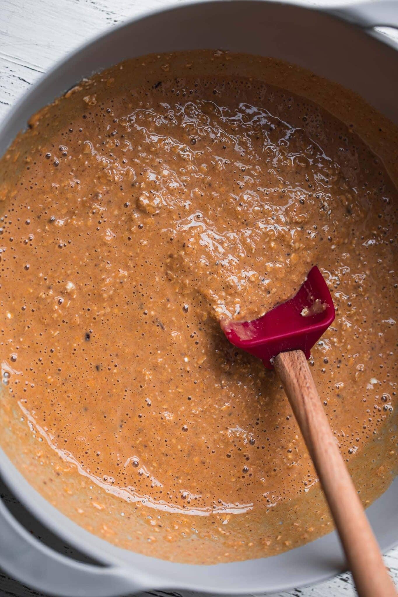 Pumpkin baked oatmeal mixture stirred together in a mixing bowl with a spatula