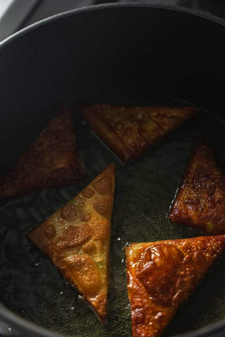 Samosas being fried in a skillet