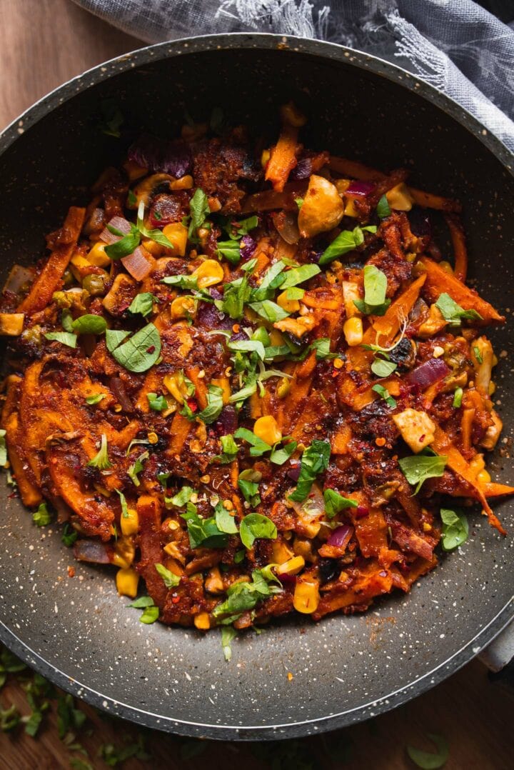 Sweet potato in a skillet with peas and sweetcorn