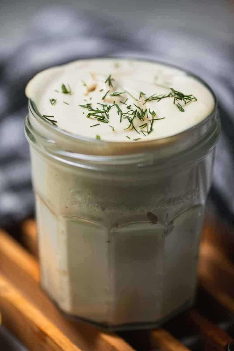 Jar of dairy-free sour cream with dill sprinkled on top