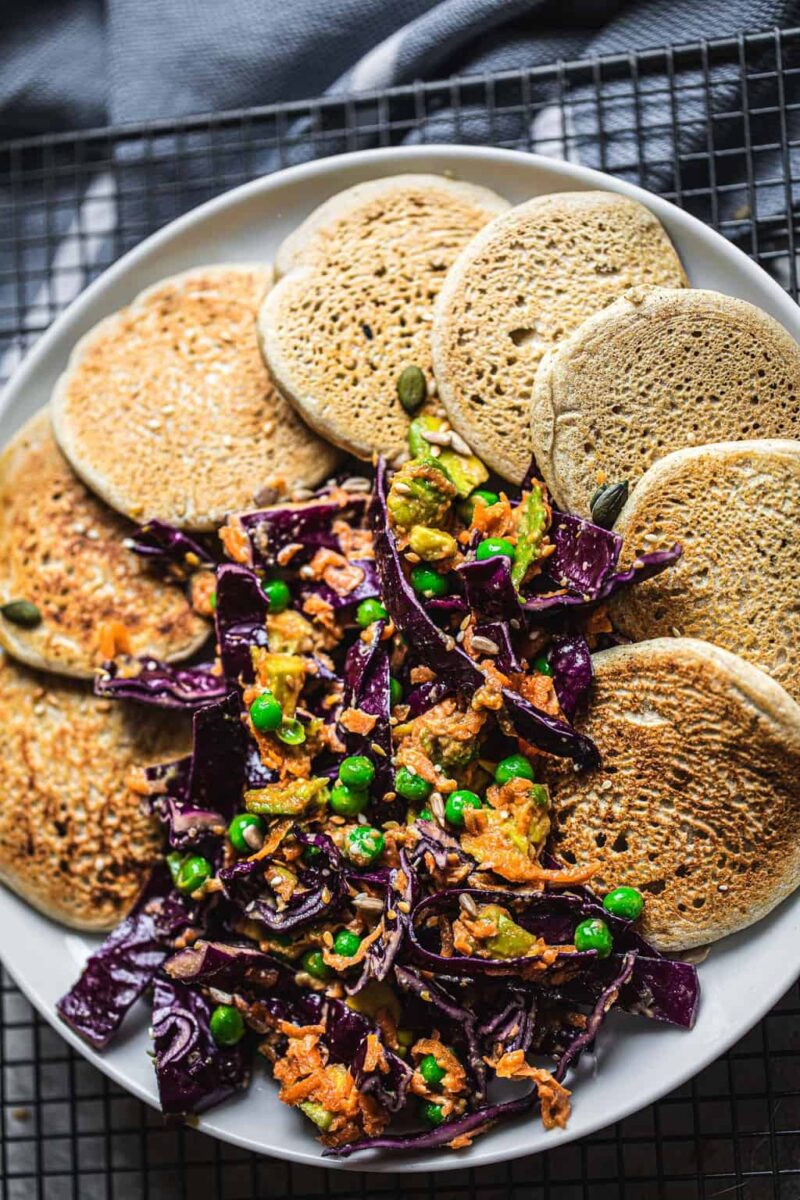 Savoury pancakes on a white plate with a purple cabbage slaw
