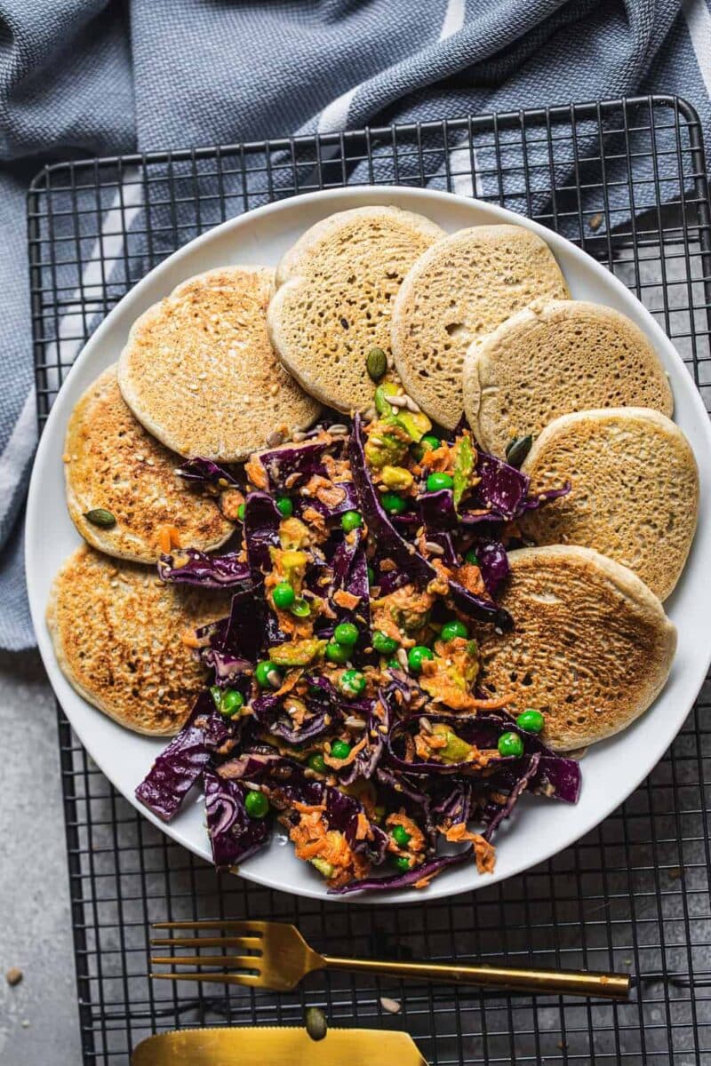 Vegan pancakes on a white flat with purple cabbage slaw