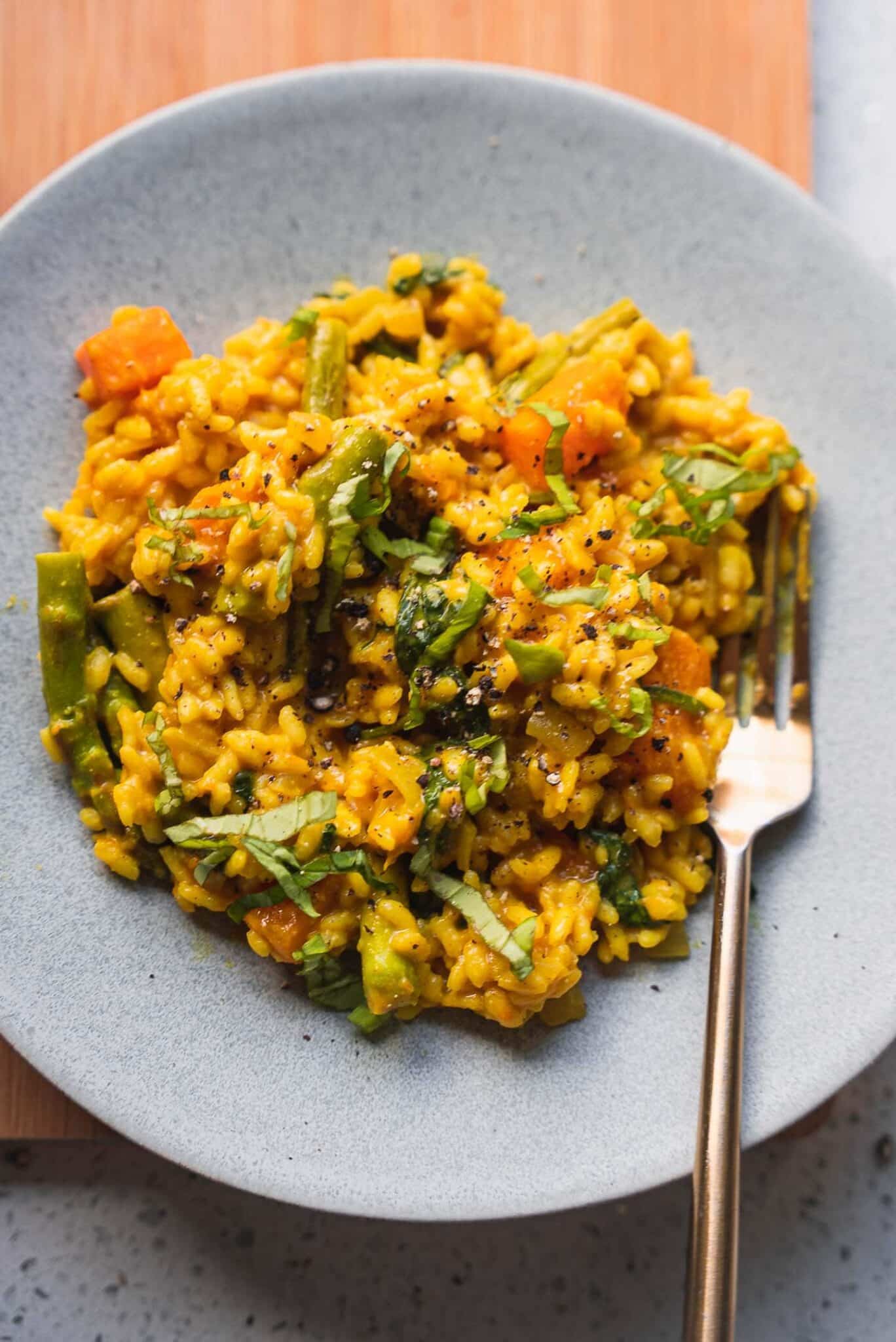 Vegan butternut squash risotto on a grey plate with a gold fork