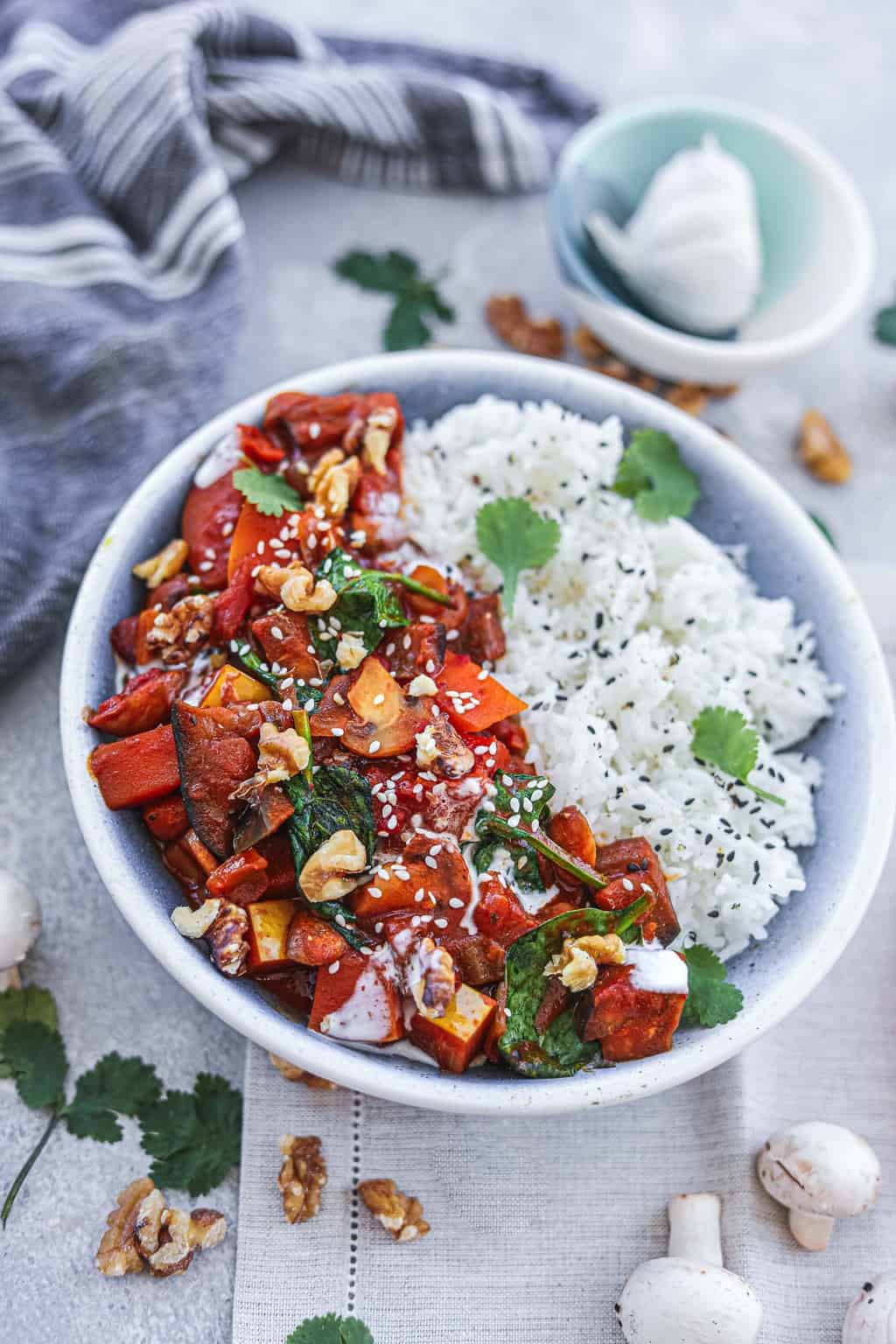 Vegan butternut squash curry with eggplant served with rice and garnished with walnuts