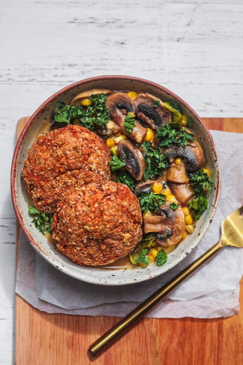 Bowl of vegan lentil burgers over a kale and mushroom stew