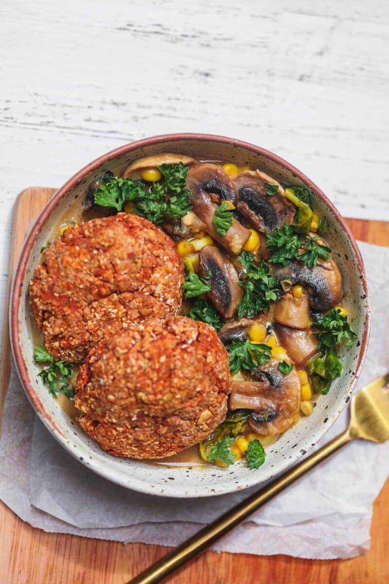 Bowl with vegan burgers over a mushroom and kale stew