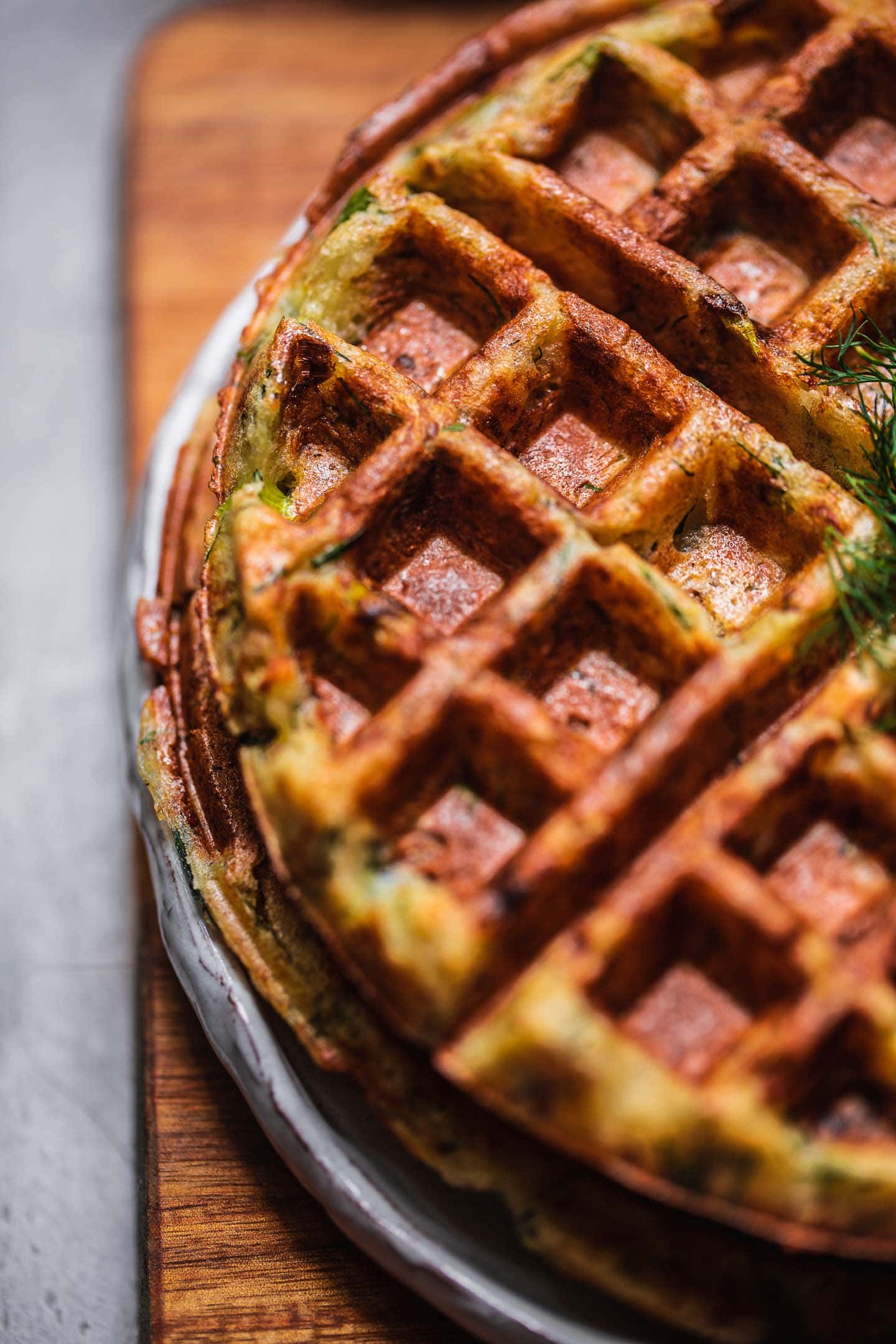 Closeup of potato waffles on a white plate and a chopping board