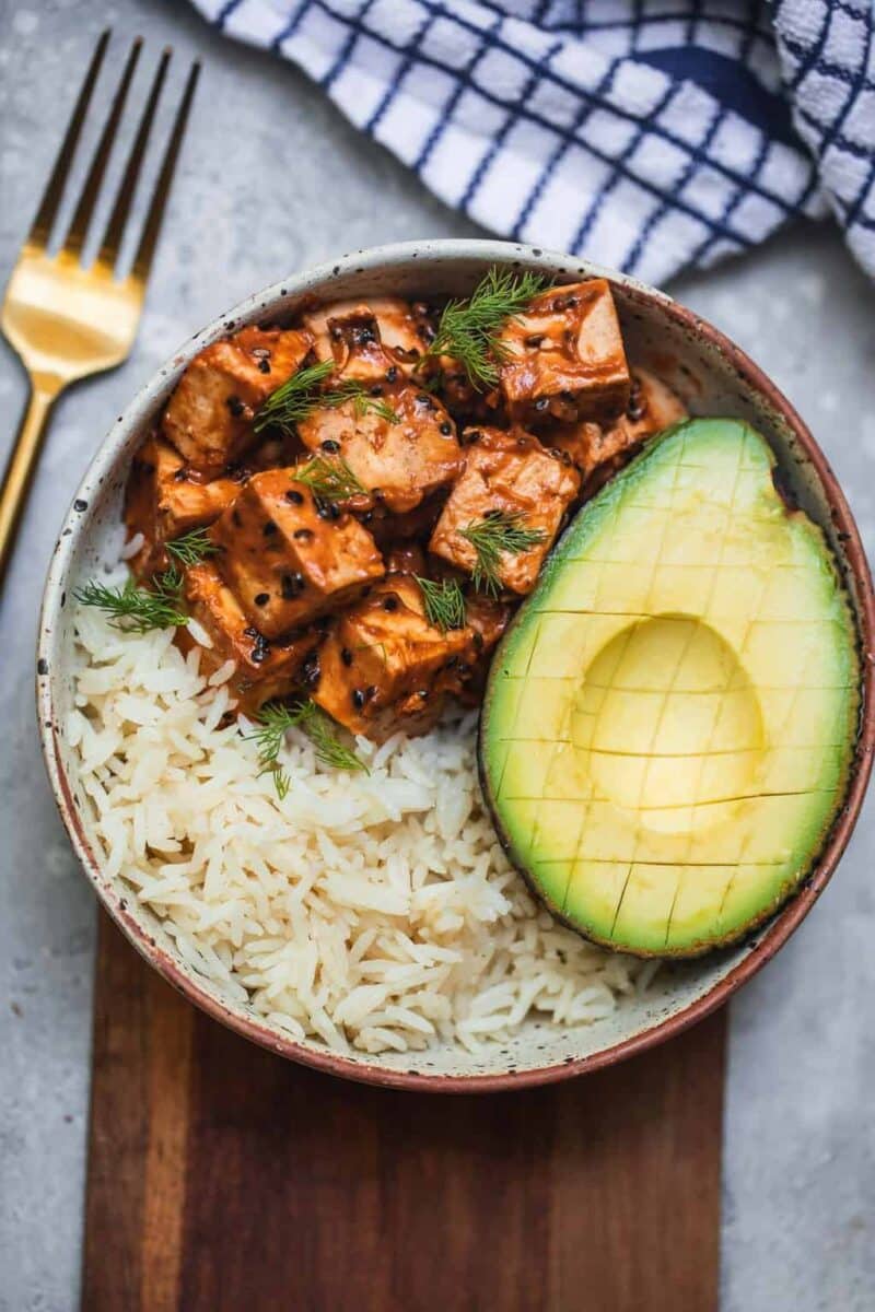 Bowl with tofu, avocado and rice on a chopping board
