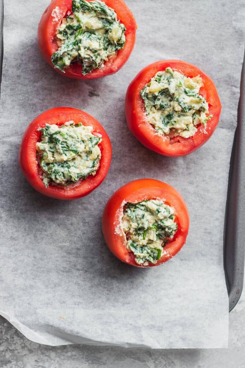 Stuffed tomatoes with rice and creamed spinach on a baking tray