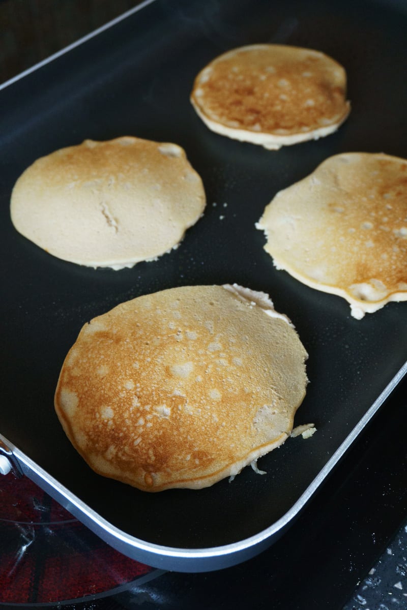 simple vegan pancakes cooking on a griddle