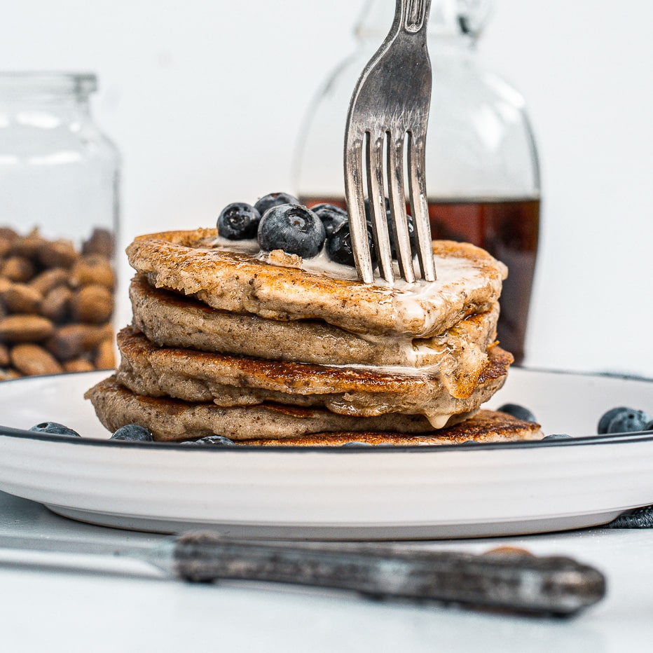 fork poking into stack of simple vegan pancakes topped with blueberries