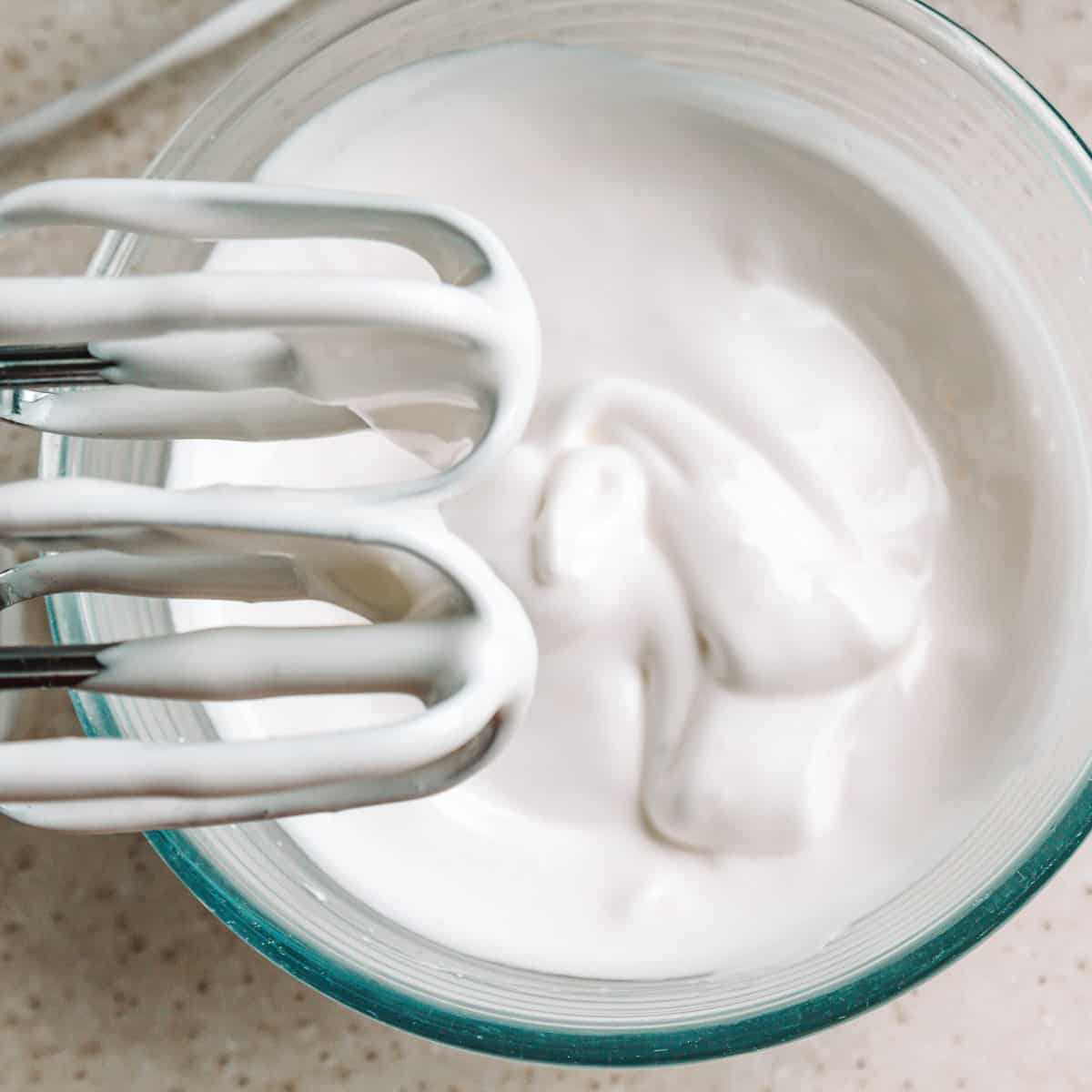 top view of hand mixer over glass bowl of vegan whipped coconut cream