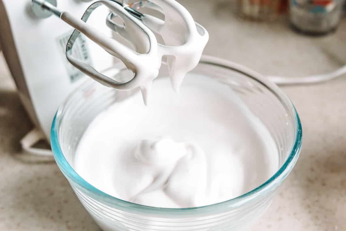 side view of hand mixer over glass bowl of vegan whipped coconut cream