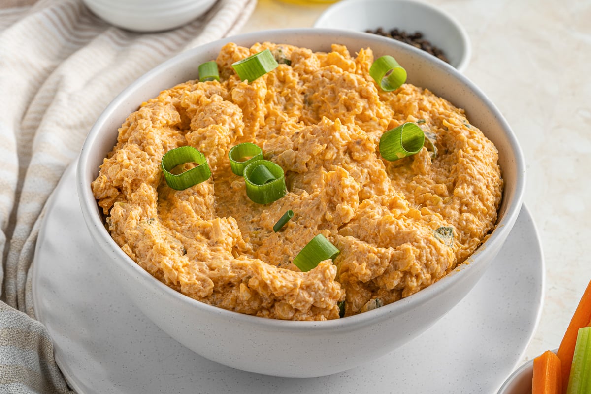 side view of bowl full of buffalo cauliflower dip topped with sliced green onions