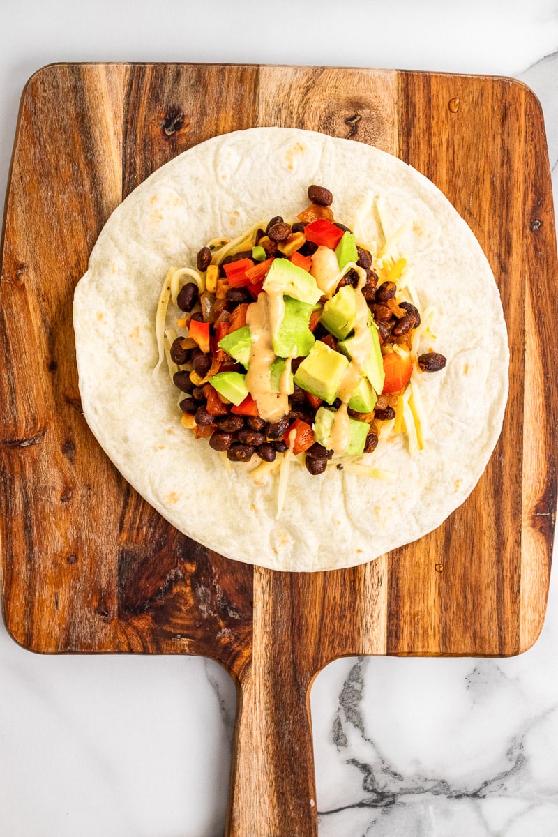 tortilla with pile of vegetarian black bean crunch wrap supreme fillings in the center