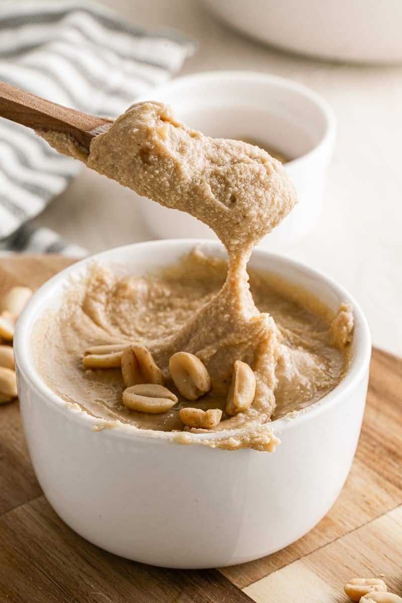 wooden spoon scooping 5-minute homemade peanut butter out of a small white bowl