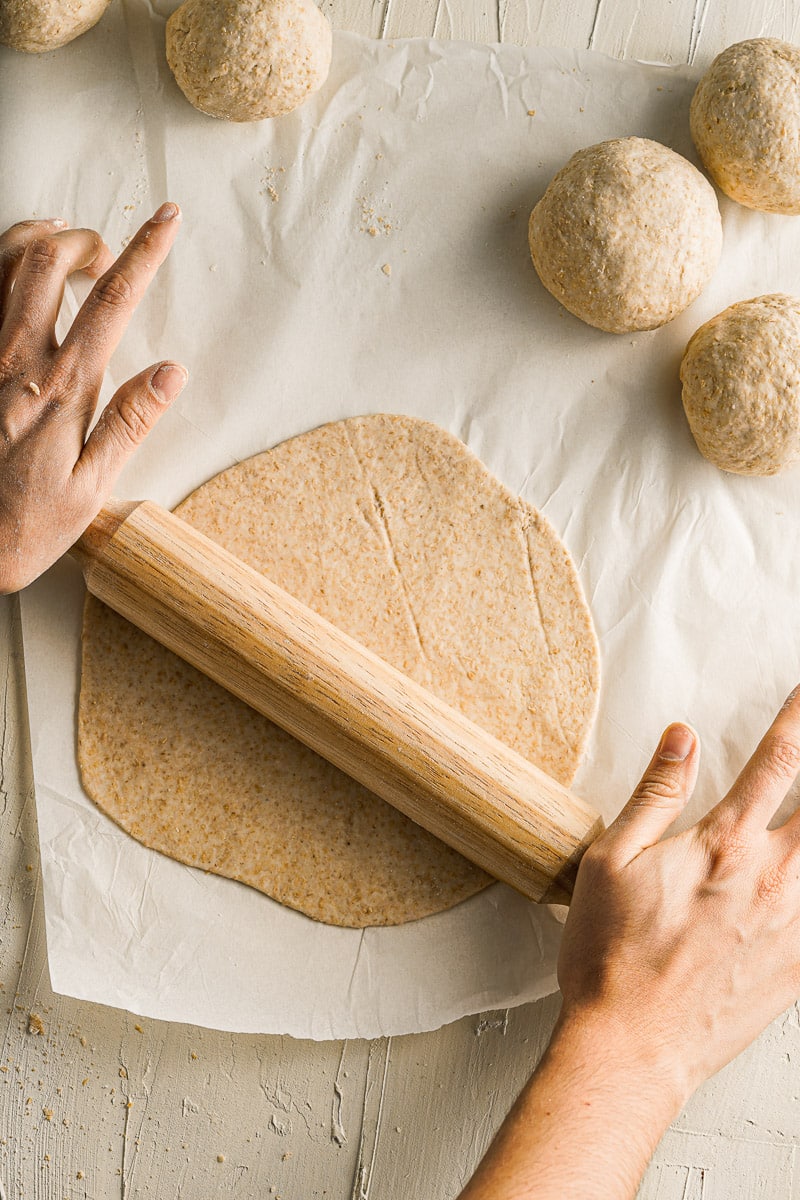 hands using a rolling pin to roll out dough for homemade tortillas