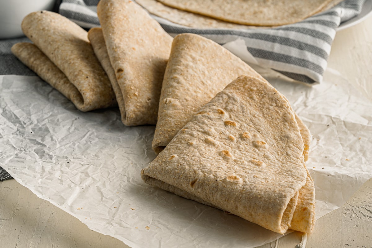 four homemade tortillas folded into triangles on a piece of wax paper