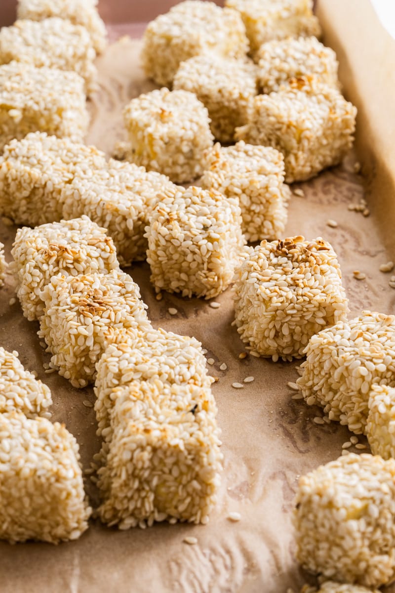 lined baking sheet with cubes of crispy sesame tofu scattered across it