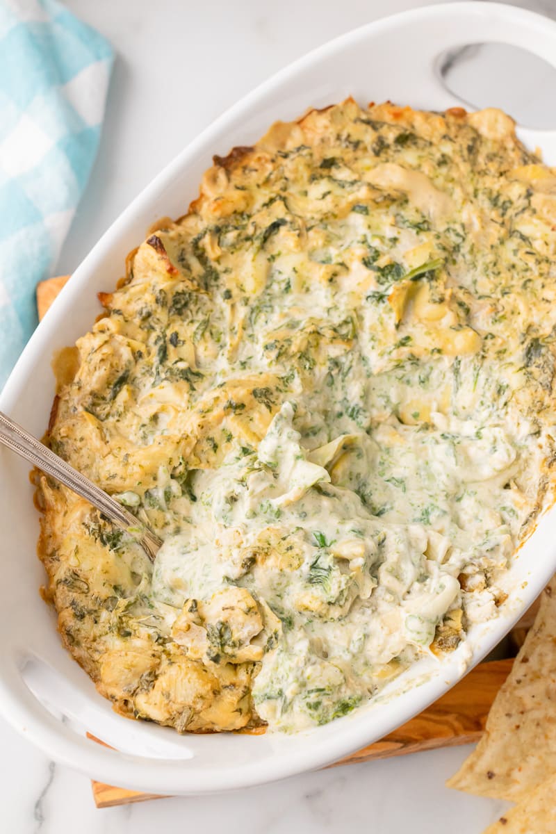 baked spinach artichoke dip without mayo in white casserole dish with metal spoon inside