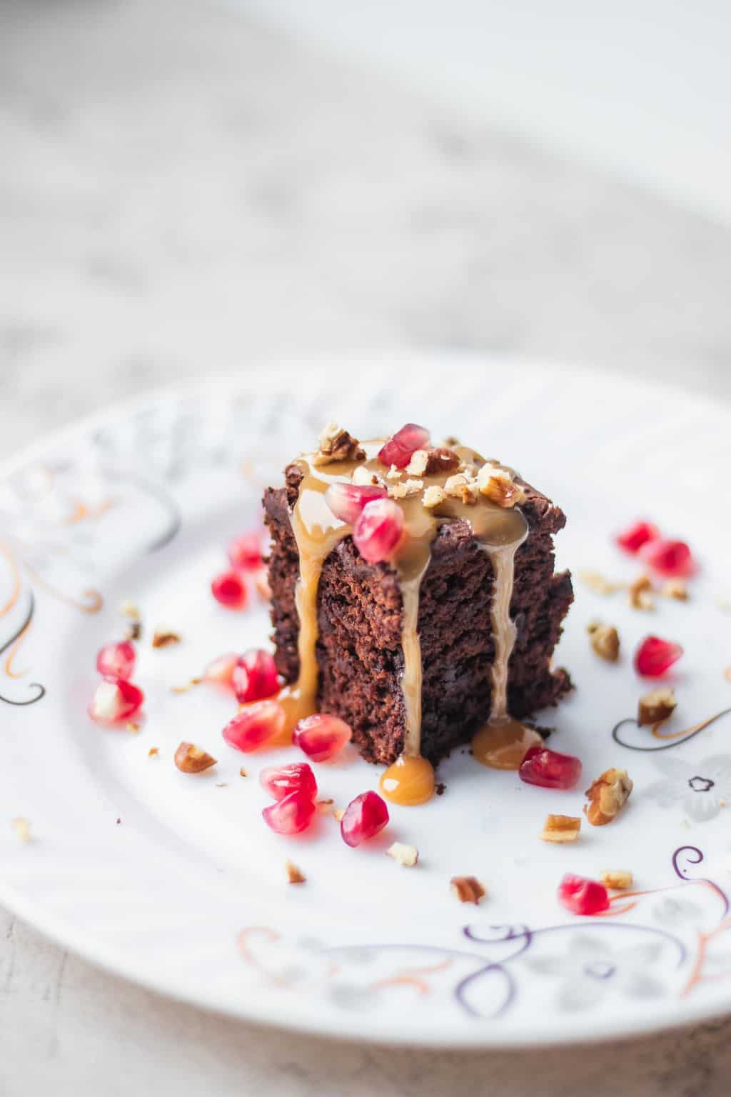 vegan caramel sauce drizzled over chocolate cake and topped with pomegranate kernels and walnuts