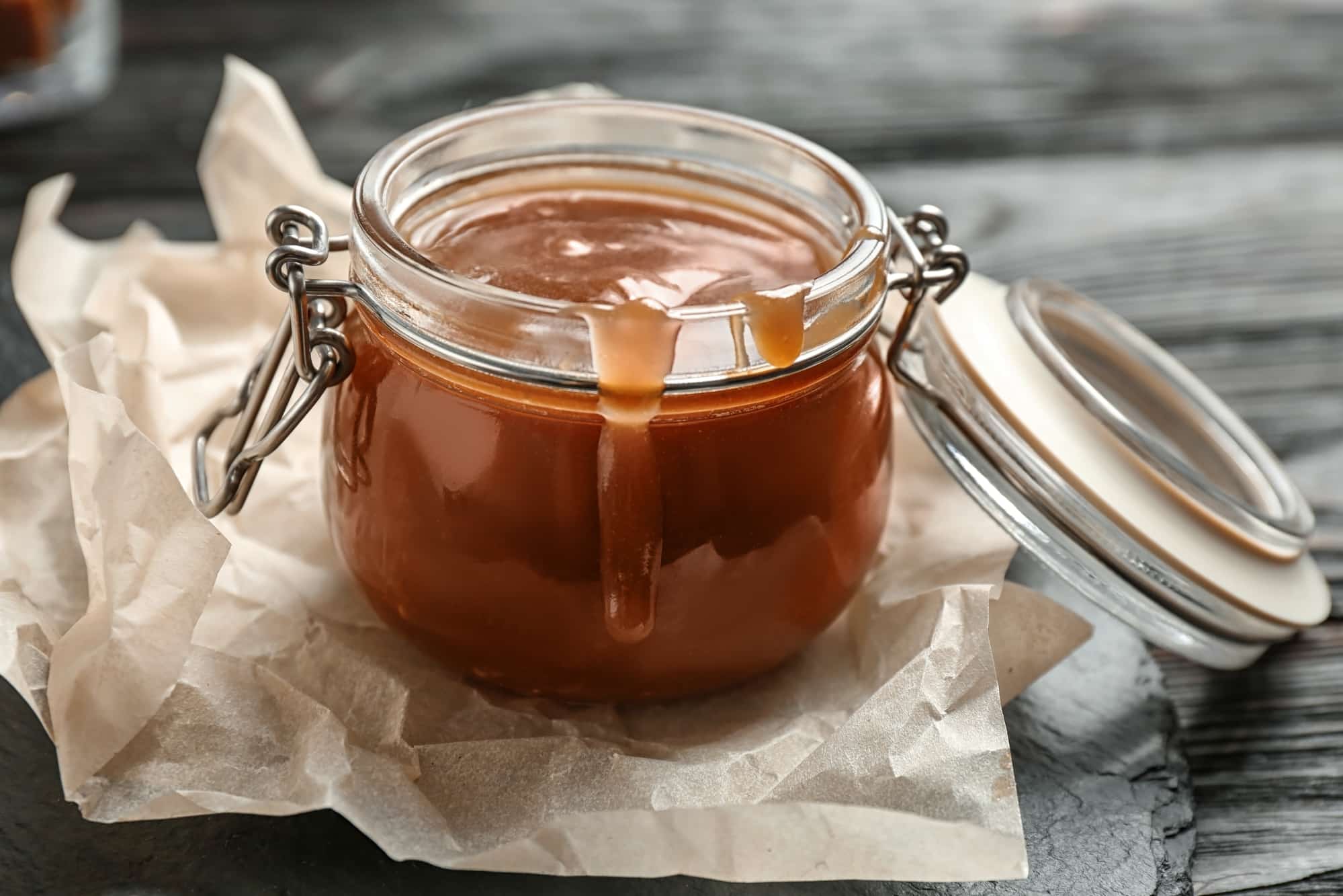 glass jar with flip top lid filled with vegan caramel sauce