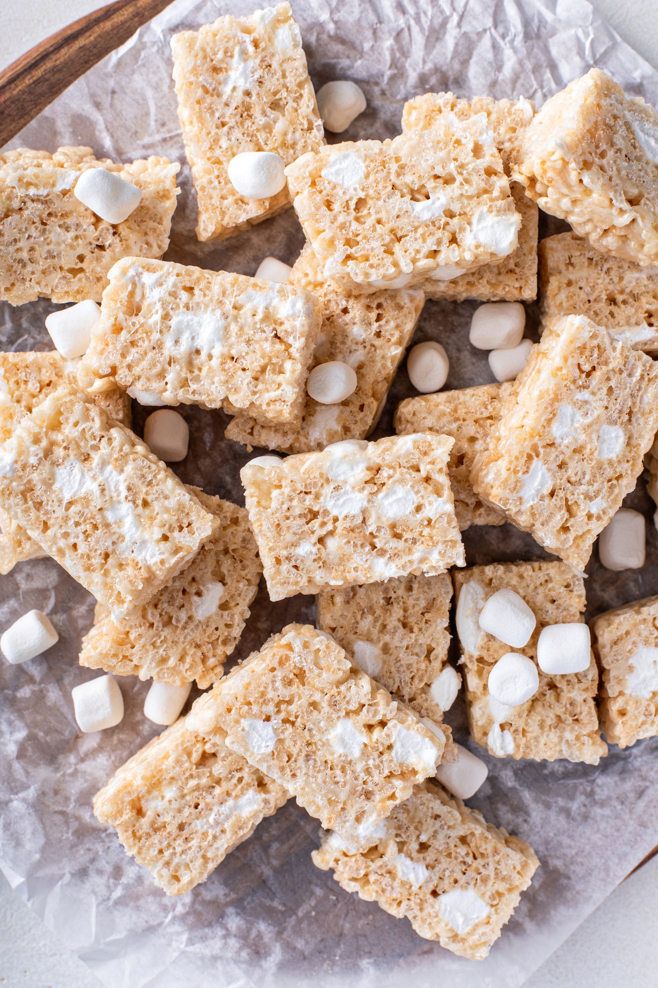 pile of vegan rice krispie treats and mini marshmallows on a sheet of wrinkly wax paper