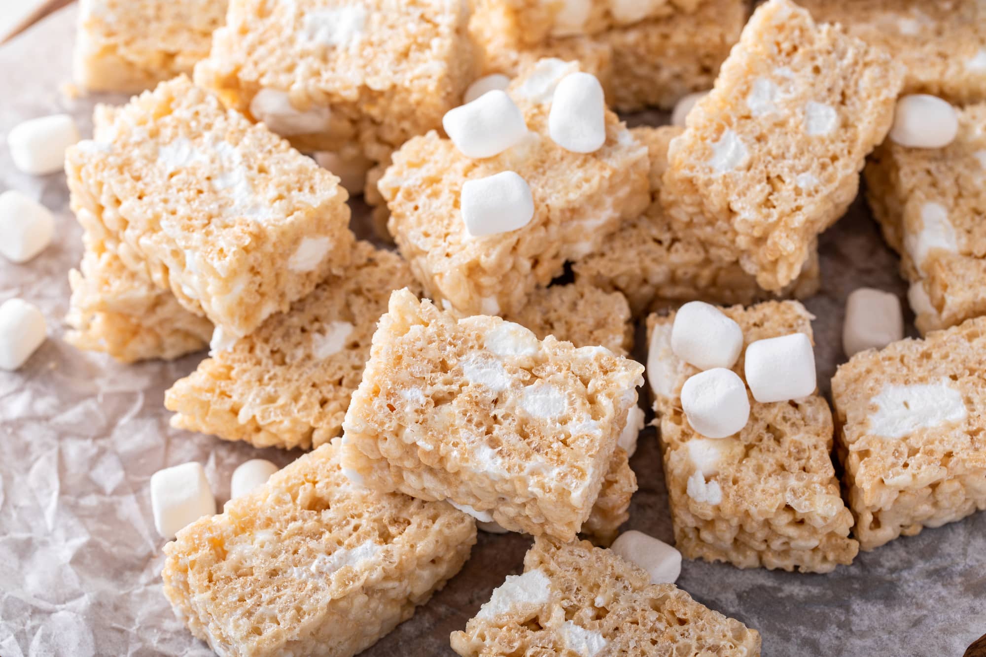 side view of pile of vegan rice krispie treats and mini marshmallows on a sheet of wrinkly was paper