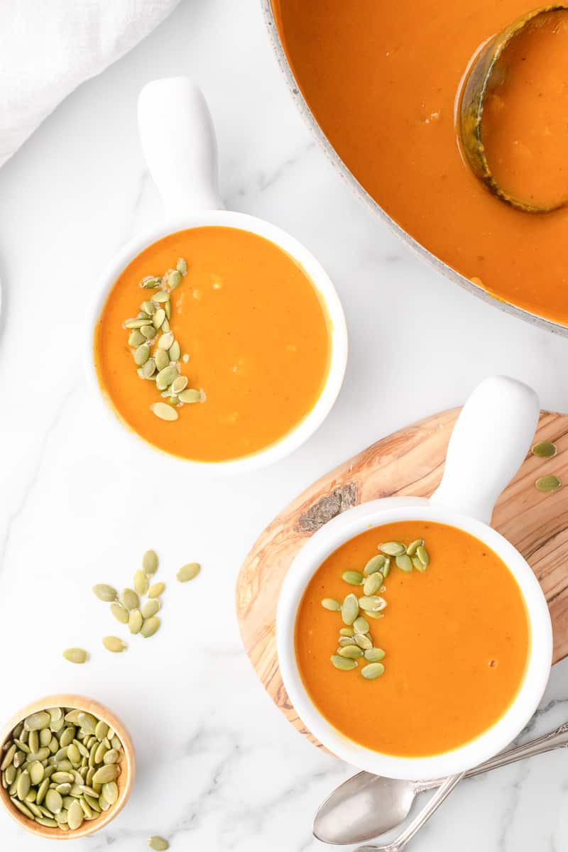 pumpkin soup in a white bowl with pepitas