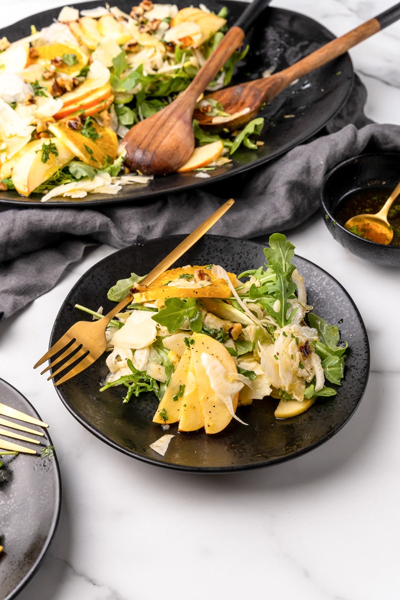 shaved fennel salad being served on a black plate