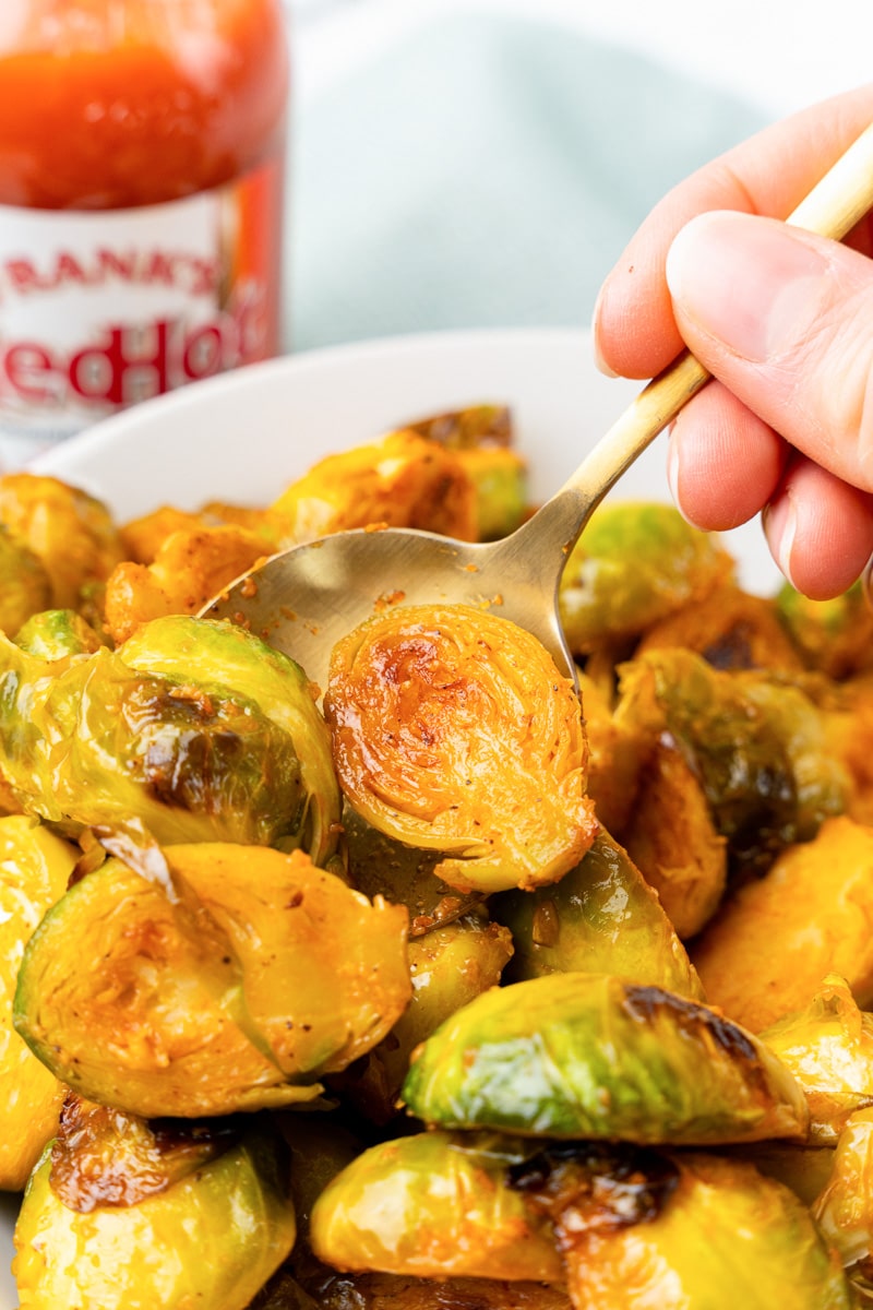 a spoon digging into a bowl of buffalo brussels sprouts