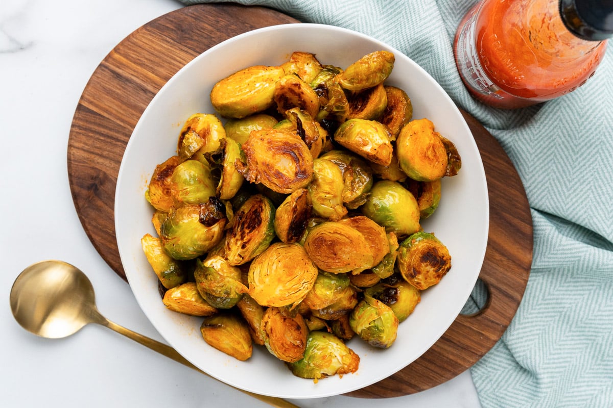 vegan buffalo brussels sprouts being served on a white platter