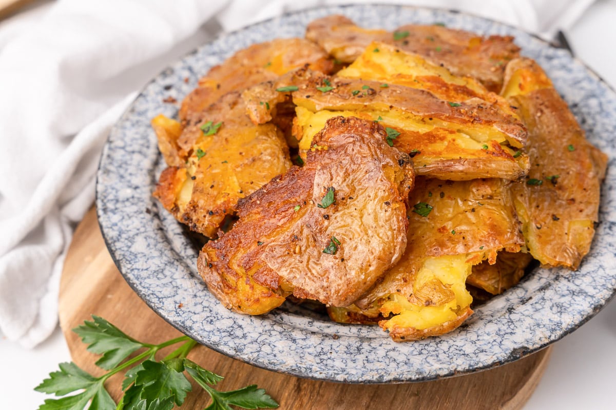 a bowl of smashed potatoes being served as a side dish