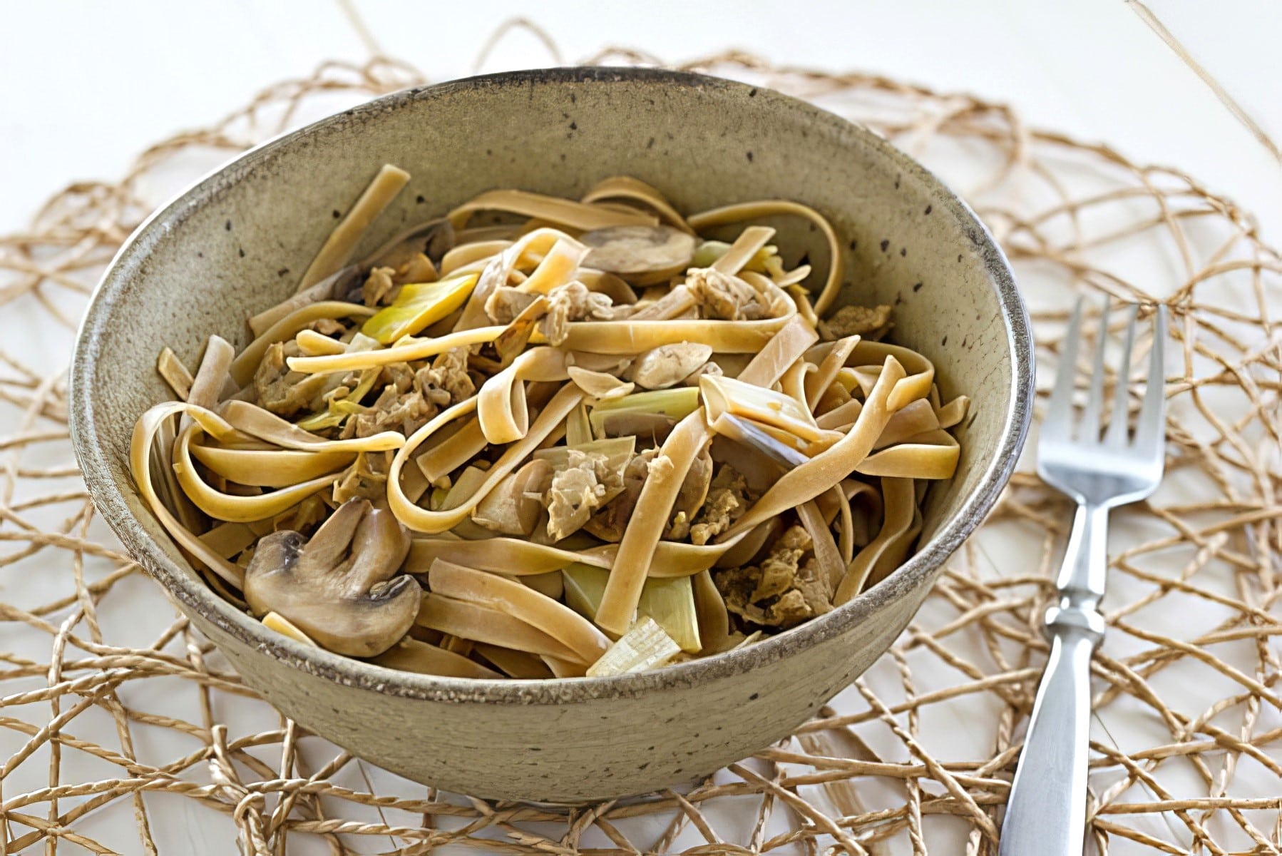 wild mushroom fettucine with vegan sausage being served in a bowl