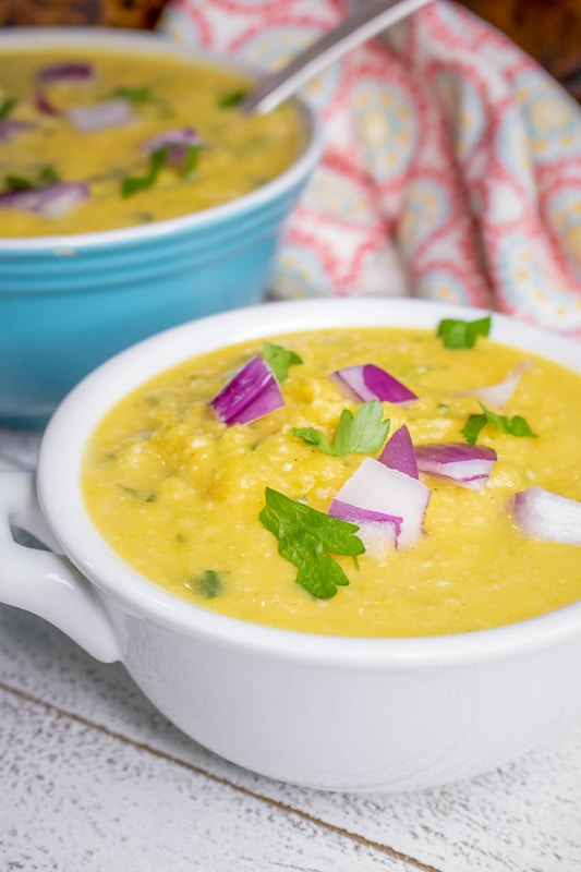 creamy vegan pumpkin soup topped with cilantro and red onions
