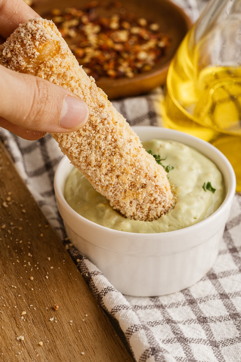 close up dipping halloumi fry into avocado mayo