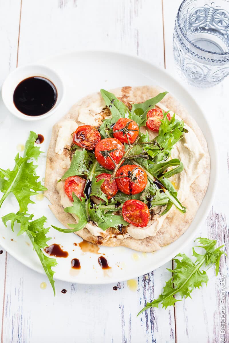 Hummus and Tomato Vegan Flatbread Pizza - A quick, easy and healthy light meal. Flatbreads are lightly toasted until crisp and topped with smooth creamy hummus, sweet cherry tomatoes, dandelion greens and tart balsamic for a satisfying meat-free lunch. | click for the recipe