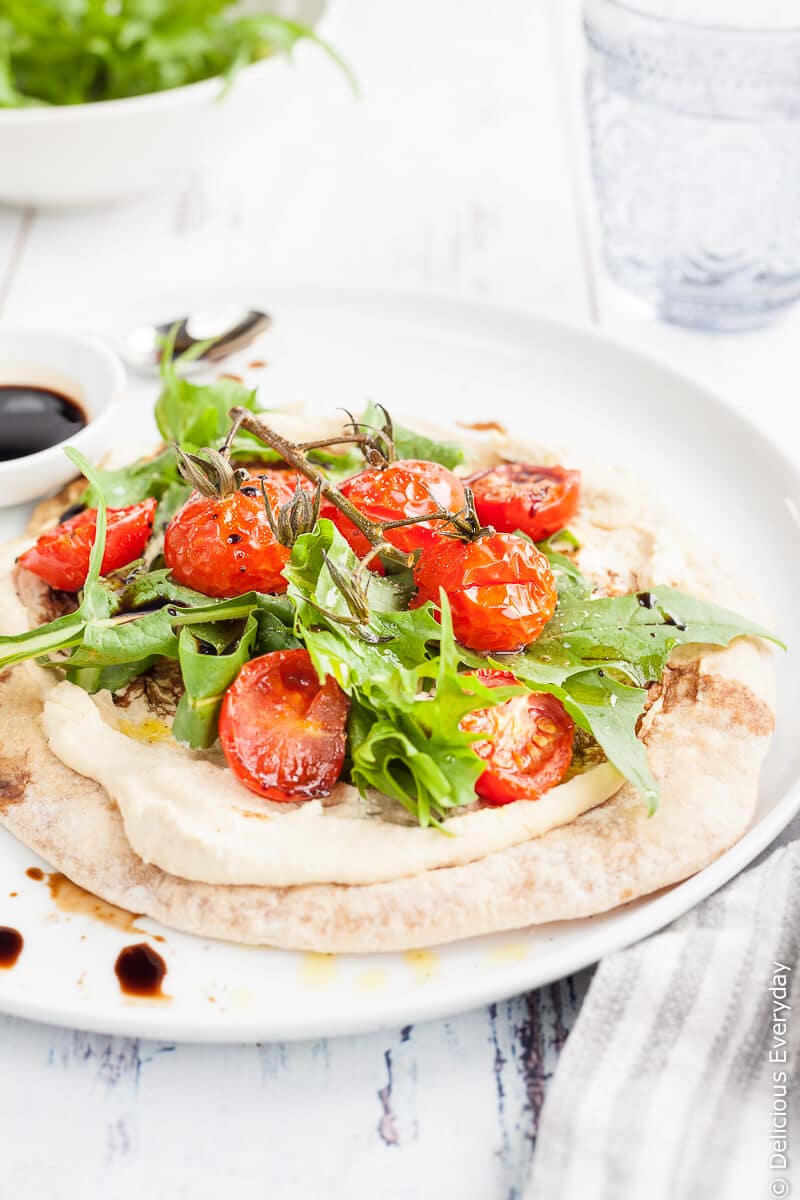 Hummus and Tomato Vegan Flatbread Pizza - A quick, easy and healthy light meal. Flatbreads are lightly toasted until crisp and topped with smooth creamy hummus, sweet cherry tomatoes, dandelion greens and tart balsamic for a satisfying meat-free lunch. | click for the recipe