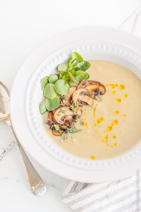 Vegan Jerusalem Artichoke Soup being served in a bowl with mushrooms and watercress