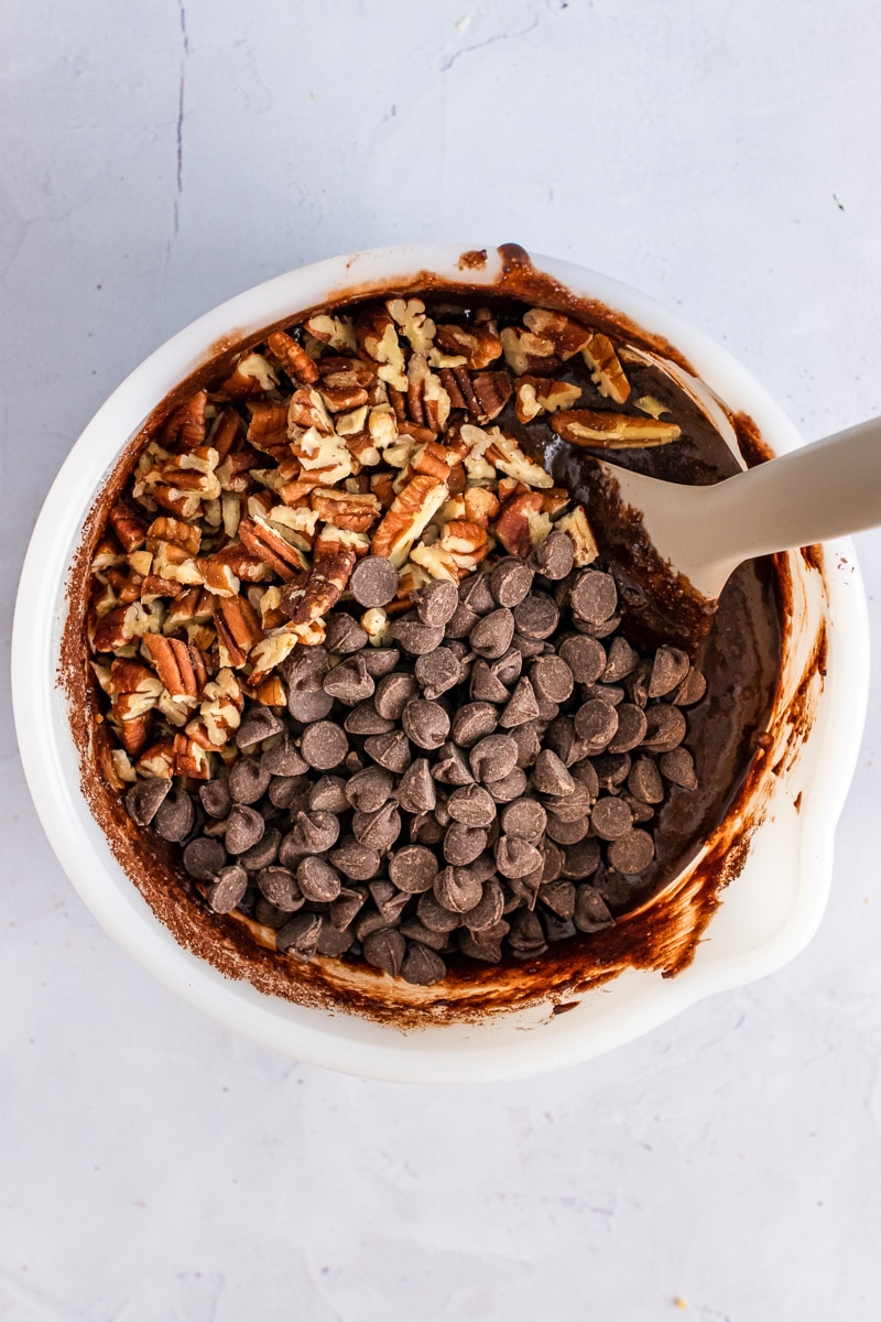 mixing nuts and chocolate chips into almond flour brownies batter