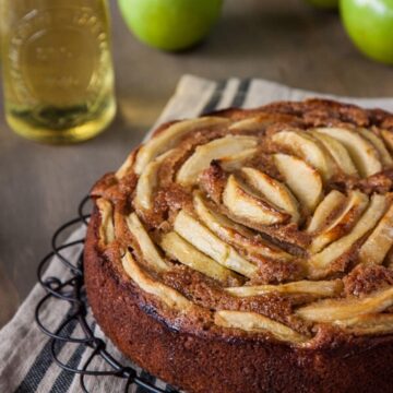 Square slice of apple cider cake topped with sliced apples and syrup