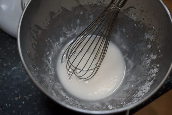 whisking lemon glaze in a mixing bowl