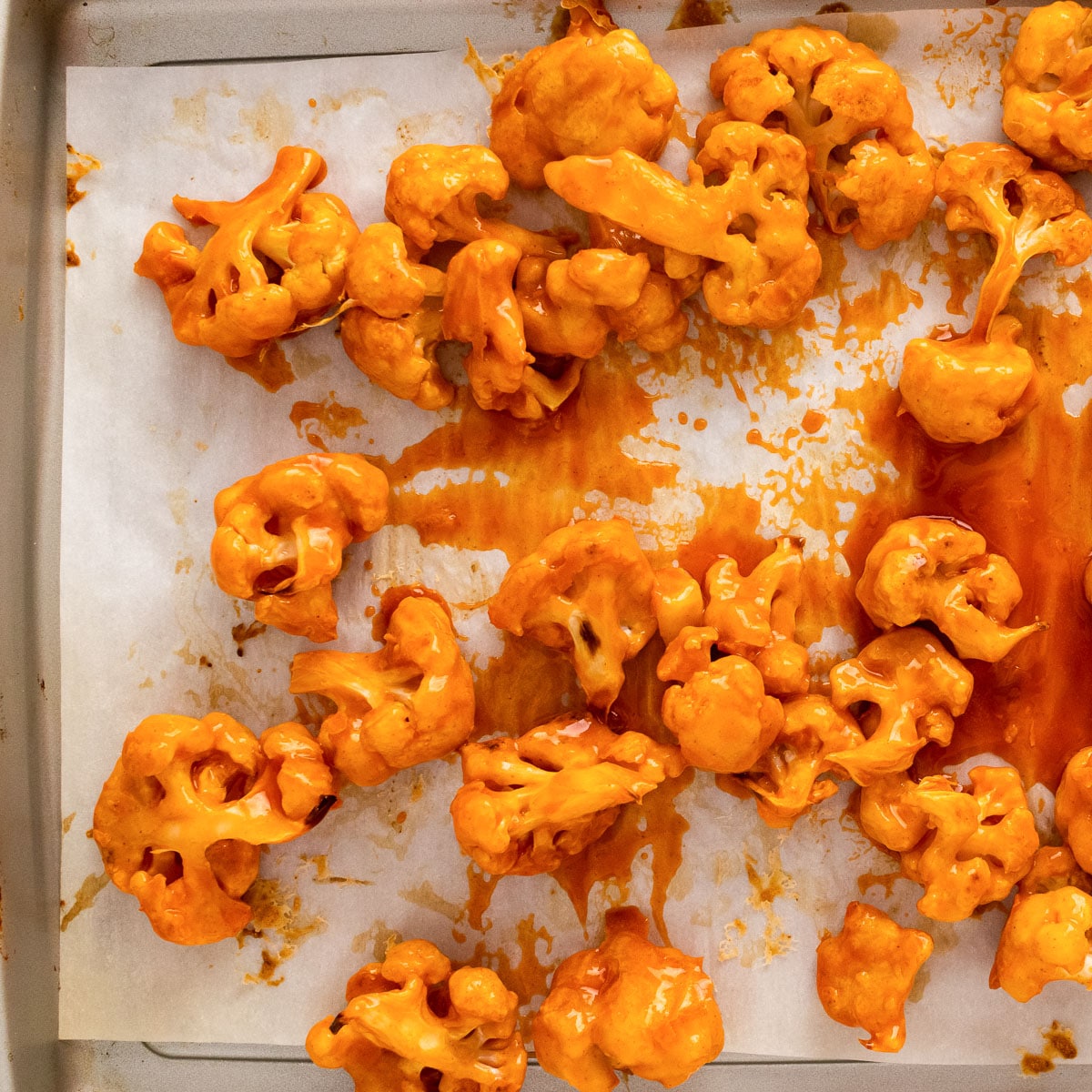 baked buffalo cauliflower with sauce on a baking sheet