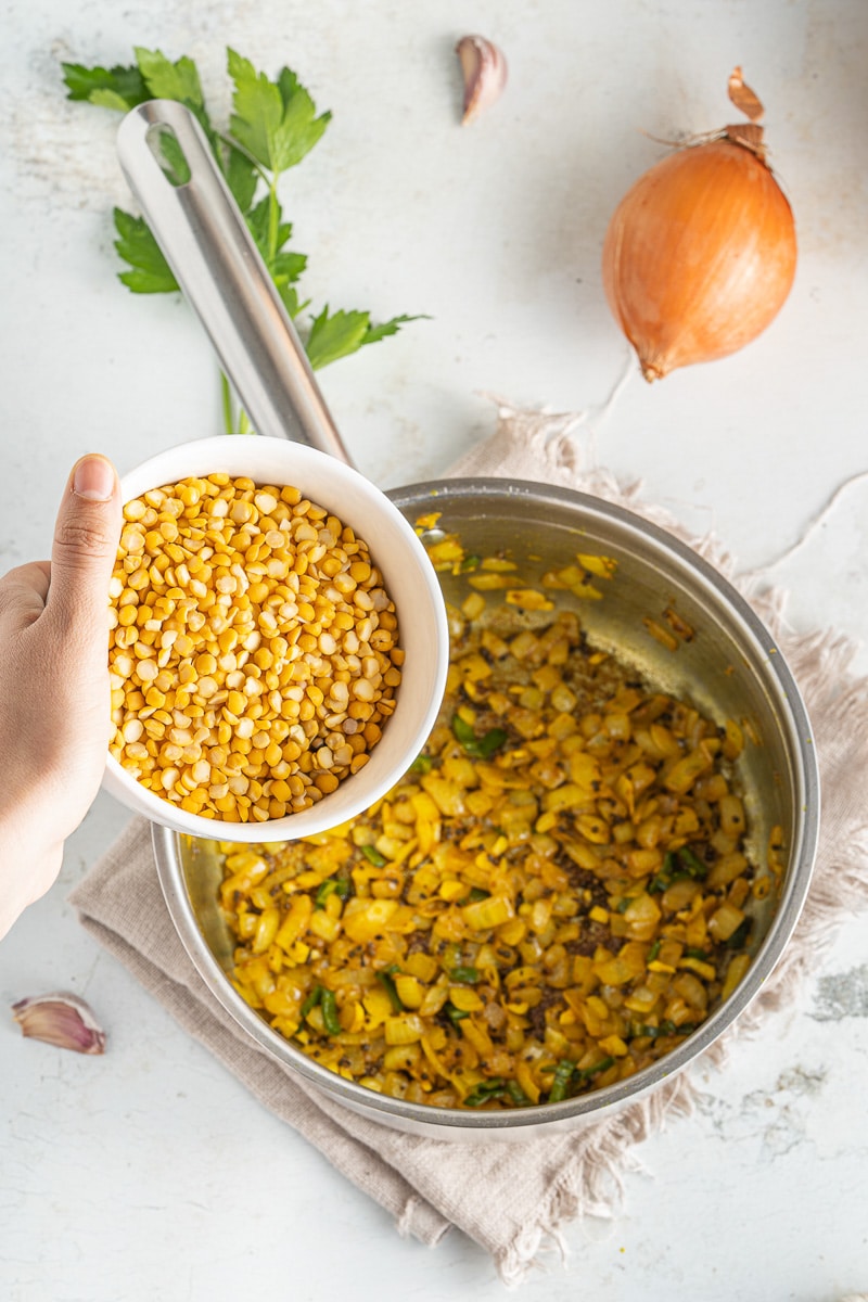 adding lentils to one-pot coconut lentil curry in cooking pot